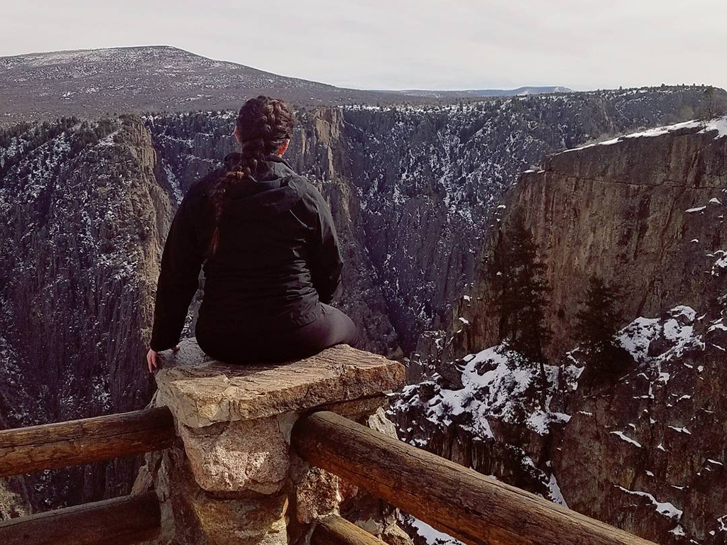 Braylee sitting on a post overlooking several cliff faces.