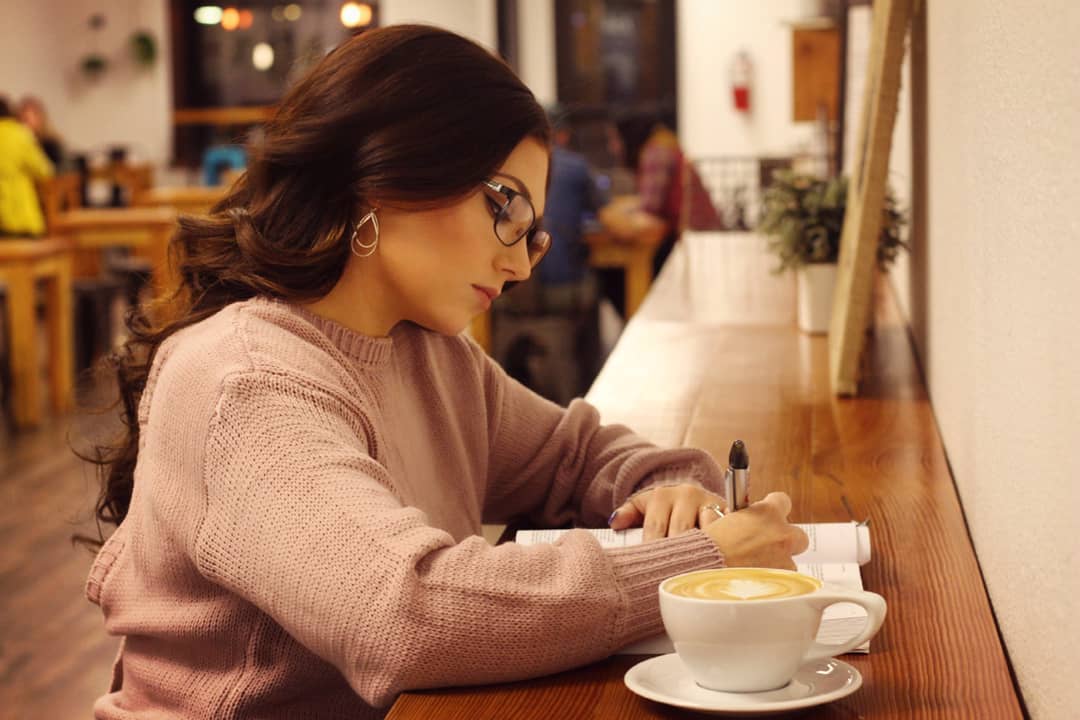 Braylee sitting at a table with a cup of coffee and her notes.